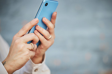 Image showing Hands, phone and space with a person closeup on a blurred gray background for social media, communication or networking. Mobile, contact and app with an adult typing or reading a text message