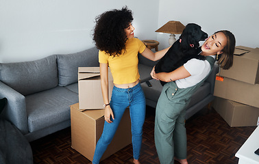 Image showing Dog, smile and gay couple in new home, play and bonding together in living room. Happy lesbian women with pet in house, apartment and moving in to real estate property, having fun and carrying animal