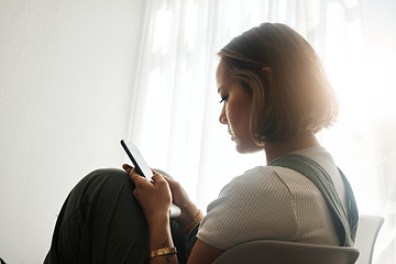 Image showing Phone, relax and young Asian woman in the living room sitting on a comfortable chair on a weekend. Calm, peaceful and female person networking on social media, mobile app or internet at apartment.