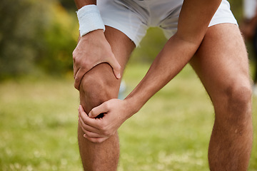 Image showing Hands, knee pain and injury with a sports man closeup outdoor for fitness, training or a workout. Exercise, accident or emergency with an athlete running on a field of grass for a marathon or cardio