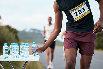 Image showing Hand, water and a marathon runner in a race or competition closeup for fitness or cardio on a street. Sports, exercise or running with an athlete grabbing a drink while outdoor on a road for training