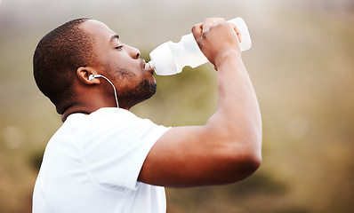 Image showing Black man, runner and drinking water with earphones, music or podcast, relax and fitness outdoor. Hydration, health and plastic bottle, listening to radio on run with exercise, mockup space and train