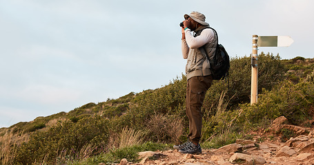 Image showing Hiker, binocular or black man on mountain in nature on trekking journey or adventure for fitness. Hiking, holiday vacation or African person walking to search in park for exercise or view on hill