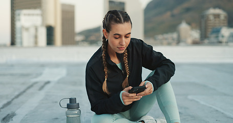 Image showing Phone, exercise and woman on social media in city on a rooftop on workout break outdoor. Fitness, communication and girl athlete networking on the internet with smartphone after cardio training