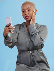 Image showing Phone, selfie and black woman beauty on app or video call isolated in studio blue background with style. Connection, African and influencer person or content creator live streaming on social media