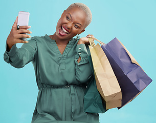 Image showing Shopping bag, studio selfie and happy black woman excited for discount promotion, sales and pose for memory photo. Photography, gift and African customer post picture to online app on blue background