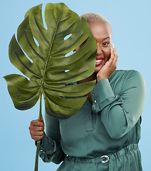 Image showing Black woman, monstera leaf and beauty in portrait, natural cosmetics and fashion on blue background. Silk green dress, eco friendly skincare and dermatology, African model glow and plant in studio