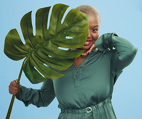 Image showing Black woman, monstera leaf and natural beauty, portrait with cosmetics and fashion on blue background. Silk green dress, eco friendly skincare and dermatology, African model glow and plant in studio