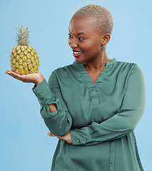 Image showing Smile, pineapple for health or nutrition and a black woman in studio on a blue background for diet. Wellness, fruit or food with a happy young person looking confident for healthy eating or detox