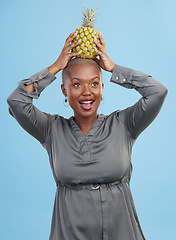 Image showing Face, balance and black woman with pineapple in studio for detox, lose weight or diet nutrition on blue background. Fruit, care and African lady nutritionist show vegan, organic and diet snack choice