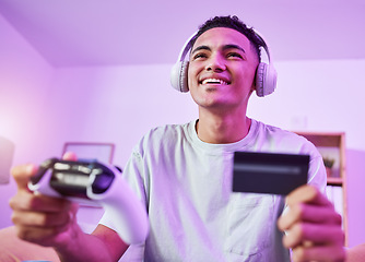 Image showing Headphones, credit card and man playing video game ecommerce for purchase with controller in virtual challenge. Internet, user experience and person or esport gamer streaming sports games online