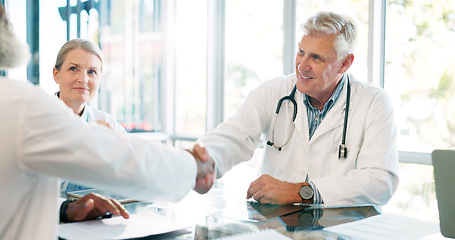 Image showing Interview, doctors shaking hands and partnership with team in meeting at hospital, senior physician and agreement. Solidarity, support and healthcare collaboration with medical professional people