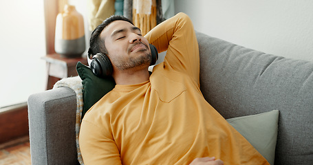 Image showing Music, headphones and asian man relax on a sofa with audio, streaming or track in his home. Earphones, radio and male with wellness app in a living room with podcast for resting, nap or day off peace