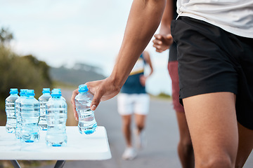 Image showing Hand, water and a marathon runner in a fitness competition or race closeup for cardio on a street. Sports, exercise or health and an athlete person with a drink while outdoor on the road for a run