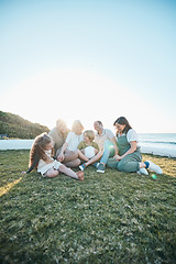 Image showing Family, grandparents and kids on grass by ocean for bonding, relationship and relax together. Nature, parents and happy grandmother, grandfather and children on holiday, vacation and travel by sea