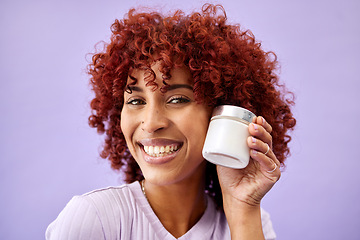 Image showing Portrait, beauty and product for skincare with a woman holding a container in studio on a purple background. Face, smile and promotion of a cream or serum for antiaging with a happy young model