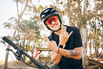 Image showing Rock sign, bike and man with helmet in forest on off road cycling workout with happiness and glasses. Portrait, person and smile with hand gestures on bicycle for exercise, challenge and competition