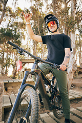 Image showing Bike, adventure and hand gesture with a sports man outdoor in a park for off ride riding during a race. Fitness, exercise and bicycle with a young athlete training for a competition in the forest