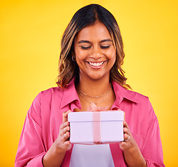 Image showing Happy woman, gift box and present for birthday, event or winning against a yellow studio background. Female person smile with prize, giveaway or celebration for surprise, package or ribbon parcel