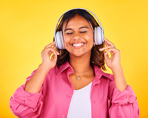 Image showing Headphones, smile and young woman in a studio listening to music, playlist or radio for entertainment. Happy, technology and female model from Mexico streaming a song or album by yellow background.