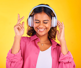 Image showing Headphones, happy and young woman in a studio listening to music, playlist or radio for entertainment. Smile, technology and female model from Mexico streaming a song or album by yellow background.