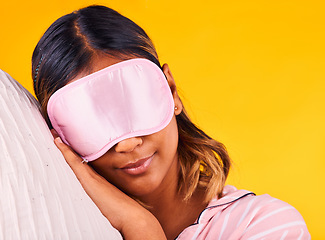 Image showing Peace, eye mask and woman sleeping in a studio with pillow for comfortable rest in pajamas. Calm, self care and young female model taking a nap, dreaming and relaxing isolated by yellow background.