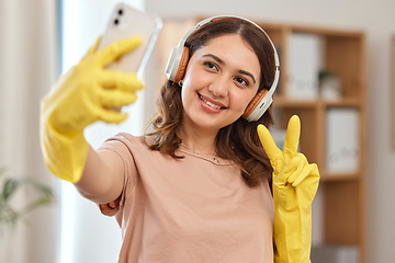 Image showing Cleaner woman, selfie and peace sign with smile, headphones and audio streaming for music in home. Happy maid girl, emoji or icon with photography, memory and profile picture on social network app