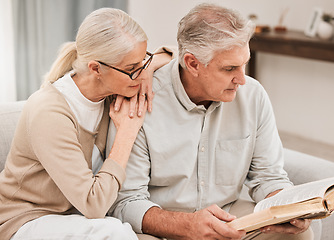 Image showing Bible study, faith and senior couple with a book in a living room relax, reading and bond at home. God, Worship and retired elderly people with scripture, guidance or gospel, love and Jesus praise