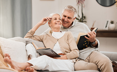 Image showing Senior, couple and reading book on a living room sofa with love, smile and retirement in a home. Elderly people, story and lounge on a couch with study for knowledge in a house happy and relax