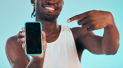 Image showing Black man pointing at phone screen, technology with advertising mockup, mobile app and ads isolated on blue background. Information, sign up and website marketing with logo design and UX in a studio