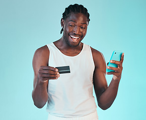 Image showing Black man, happy with smartphone and credit card, e commerce and payment success or win on blue background. Fintech, online shopping and website discount, giveaway with customer experience in studio