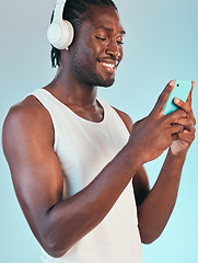 Image showing Smartphone, headphones and black man listening to music, smile with audio streaming and chat isolated on blue background. Happiness, sound and mobile app, podcast or radio with connectivity in studio