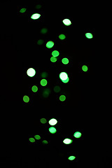 Image showing Green light, bokeh and glow on dark background isolated on a mockup space. Blur, black backdrop and defocused shine, sparkle or glitter at night for Christmas, holiday or party with magic color dots