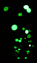 Image showing Green, glitter and bokeh in a studio with dark background for celebration, event or party. Confetti, lights and color sparkles for magic, shine or glow for festive by black backdrop with mockup.