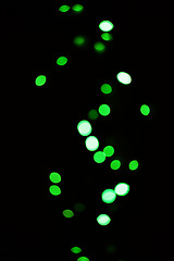 Image showing Green light, bokeh and glow on dark background isolated on a mockup space. Blur, black backdrop and defocused shine, sparkle or glitter at night for Christmas, holiday or party with magic color dots