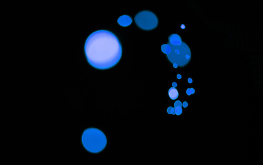 Image showing Bokeh, blue particles and lights on dark background with pattern, texture and mockup with cosmic aesthetic. Night lighting, sparkle dots and glow on black wallpaper with space, color shine and flare.