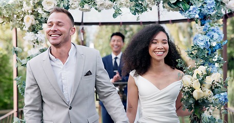Image showing Couple, wedding and walk with flower confetti for event, celebration and outdoor in nature. Girl, happy interracial marriage and floral bouquet in park, holding hands or fist in air, pride or party