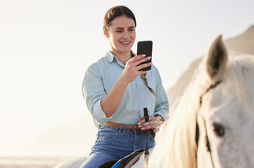 Image showing Horse riding, phone and woman on beach with pet for travel using social media, website and web for chatting. Texting, smile and happy person or rider with animal on vacation or holiday at sunrise