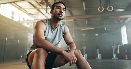 Image showing Fitness, breathing and sweating with a tired man in the gym, resting after an intense workout. Exercise, health and fatigue with a young athlete in recovery from training for sports or wellness
