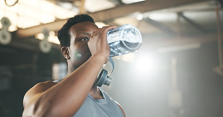 Image showing Black man at gym, water bottle and relax to hydrate in muscle development, strong body and fitness. Commitment, motivation and bodybuilder with drink in workout challenge for health and wellness.
