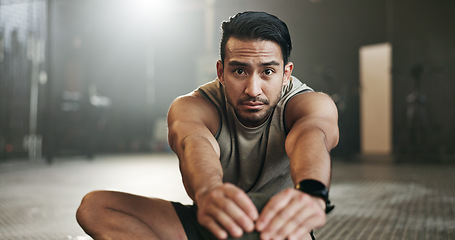 Image showing Man stretching on floor of gym for strong body, muscle development or balance in power fitness. Commitment, motivation and focus on ground, bodybuilder in energy training workout and exercise mindset