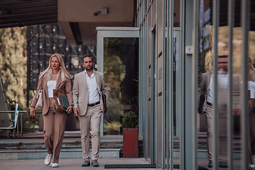 Image showing Modern business couple after a long day's work, walking together towards the comfort of their home, embodying the perfect blend of professional success and personal contentment.