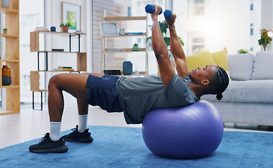 Image showing Fitness, home workout and a black man lifting weights on an exercise ball for strong muscles in the living room. Gym, health and a male athlete training in a house for wellness, strength or lifestyle