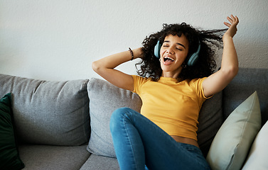 Image showing Music, headphones and happy woman sing on a sofa with podcast, album or audio track at home. Radio, earphones and female person in living room with feel good fun subscription, streaming or freedom