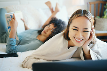 Image showing Laptop, smile and a lesbian couple reading in bed while together in their home on the weekend. Diversity, computer and a happy lgbt woman with her girlfriend in the bedroom for love or bonding