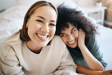 Image showing Love, happy and portrait of lesbian couple relaxing on bed for bonding together on a weekend. Smile, romance and young interracial lgbtq women resting in the bedroom of modern apartment or home.