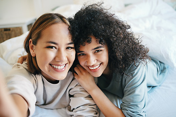 Image showing Smile, selfie and portrait of lesbian couple on bed for bonding, resting or relaxing together. Happy, love and young interracial lgbtq women taking picture in the bedroom of modern apartment or home.