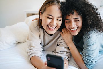 Image showing Cellphone, relax and young lesbian couple in bed networking on social media, mobile app or the internet. Happy, technology and interracial lgbtq women scroll on a phone in bedroom at modern apartment