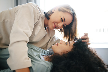 Image showing Love, happy and lesbian couple with intimate moment on bed for bonding or relaxing together. Smile, romance and young interracial lgbtq women with affection in the bedroom of modern apartment or home