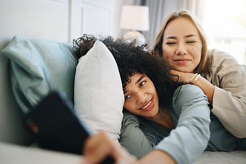 Image showing Cellphone, relax and young lesbian couple on a bed networking on social media, mobile app or the internet. Happy, technology and interracial lgbtq women scroll on cellphone in bedroom at apartment.